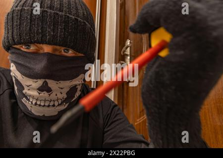 Cambriolage, un voleur masqué dans une Balaclava ouvre la porte Banque D'Images
