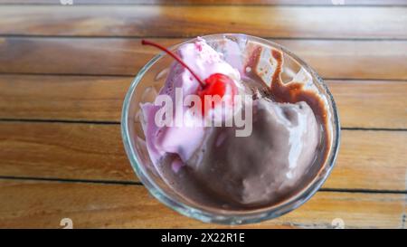 Crème glacée aromatisée au chocolat et à la fraise avec cerise sur le dessus Banque D'Images
