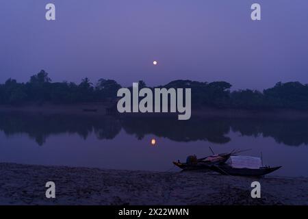 La lune se reflète sur le canal d'eau avec un bateau de pêche dans le paysage des Sundarbans indiens au crépuscule au petit matin, la plus grande mangrove Banque D'Images