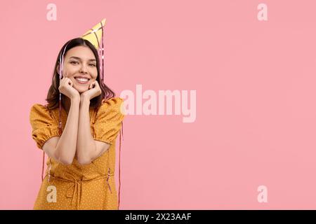 Heureuse jeune femme dans le chapeau de fête sur fond rose Banque D'Images