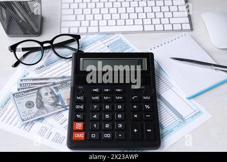 Comptabilité fiscale. Calculatrice, documents, argent, papeterie et lunettes sur table gris clair Banque D'Images
