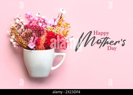 Bonne fête des mères. Tasse blanche de café avec diverses fleurs et le texte Happy Mothers Day sur fond rose Banque D'Images