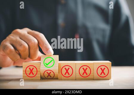 Retourner le cube en bois de la croix rouge pour corriger la tique à la main symbolisant le concept d'approbation de projet Banque D'Images