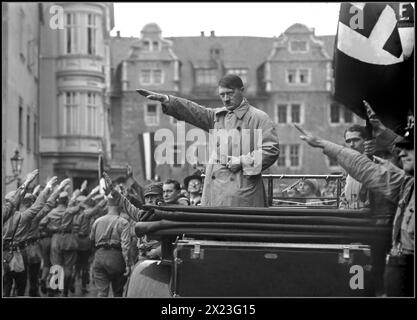 Années 1930 Adolf Hitler en vêtements civils debout à l'arrière de sa voiture Mercedes à toit ouvert, avec une expression sévère, donnant un salut Heil Hitler à l'armée paramilitaire de Sturmbleitung qui passait devant. Rudolf Hess figurait sous le drapeau swastika. Hermann Goering est également présent devant la Mercedes. À côté de Goering se trouve Julius Streicher, un antisémite notoire qui a lancé le journal Der Sturmer pour diffuser de la propagande nazie antisémite. Nurnberg Nuremberg Rallye Nazi Gemany années 1930 Banque D'Images