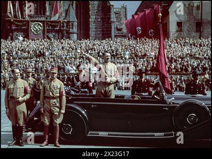 Années 1930 Adolf Hitler en uniforme de Sturmbleitung debout à l'arrière de sa voiture Mercedes à toit ouvert, une image couleur rare d'Hitler donnant un salut Heil Hitler à l'armée paramilitaire de Sturmbleitung qui passe devant. Rudolf Hess présenté à gauche par Mercedes car. Nurnberg Nuremberg Rallye nazi Gemany années 1930 Leibstandardiste SS Adolf Hitler ('Life Guards SS Adolf Hitler' ; LSSAH) une unité de protection SS d'élite derrière Banque D'Images