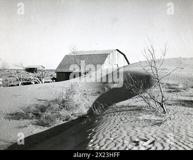 1936, Liberal, Kansas - Une dérive de poussière menace d'engloutir cette grange pendant les tempêtes de poussière de 1936. Banque D'Images
