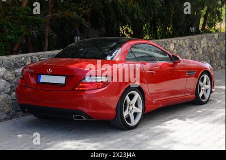 Gaziveren Chypre 04.18.2024-rouge Mercedes Benz dans le parking près de la maison 1 Banque D'Images