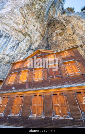 Description : prise de vue à faible angle de la cabane en bois suisse Gasthaus Aescher-Wildkirchli sous un mur de roche massif surpenchant. Seealpsee, Appenzell, Suisse, E Banque D'Images