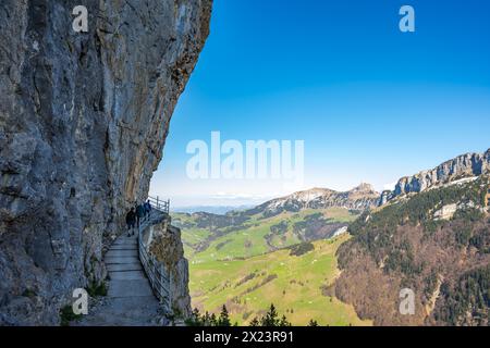 Description : les touristes marchent sur le sentier alpin de Äscher à Ebenalp sous un grand mur rocheux avec Hoher kasten mountin en arrière-plan. Seealpsee, Appenz Banque D'Images