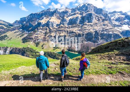 Description : touristes sur un sentier de randonnée à une prairie verte overloop le lac alpin et la formation de montagne rocheuse en arrière-plan. Seealpsee, Appenzell, Banque D'Images