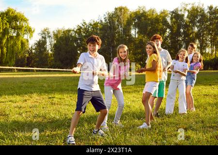 Heureux enfants joyeux jouant dans le remorqueur de la guerre avec une corde dans le parc d'été dans la nature dans le camp d'enfants. Banque D'Images