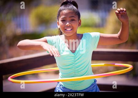 Fille heureuse, portrait et jouer avec cerceau en plastique au parc pour le jeu amusant, l'activité ou l'exercice en plein air. Jeune adolescent ou personne féminine avec sourire pour Banque D'Images