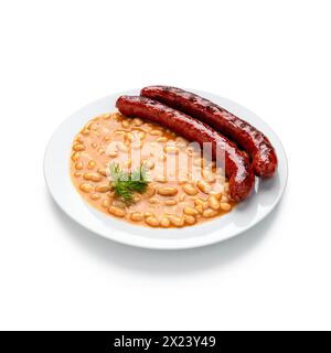 Laissez-vous tenter par le charme rustique d'un copieux ragoût de haricots avec de succulentes saucisses, servi avec élégance sur une assiette blanche immaculée. Ce plat réconfortant apporte la guerre Banque D'Images