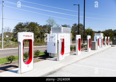 Une rangée de bornes de recharge Tesla blanches et rouges dans un parking sans véhicules. Banque D'Images