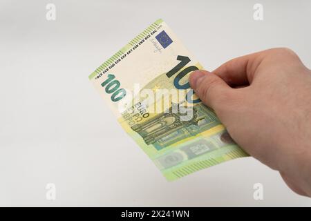 Homme tenant 100 EUR billet de banque monnaie papier Euro isolé sur fond blanc Banque D'Images