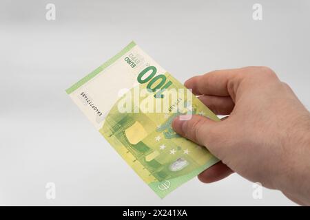 Homme tenant 100 EUR billet de banque monnaie papier Euro isolé sur fond blanc Banque D'Images