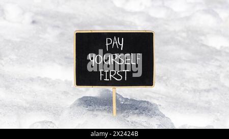 Premier symbole payez-vous. Les mots de concept vous payez d'abord sur un beau tableau noir de craie noire. Beau fond de neige blanc. Et payez-vous Banque D'Images