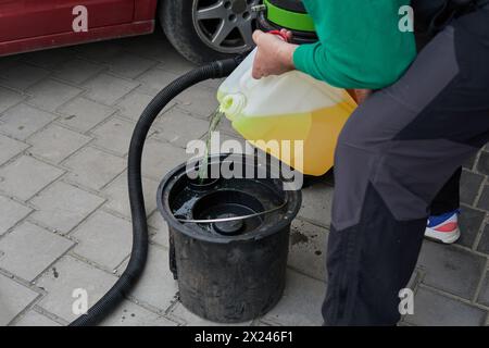Verser du liquide de nettoyage dans un seau à partir d'une bouteille pour aspirateur d'extraction professionnel Banque D'Images