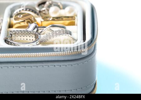 Boîte à bijoux ouverte bleu clair avec accessoires pour femmes, boucles d'oreilles et bagues. Macro gros plan, isolé sur fond blanc Banque D'Images