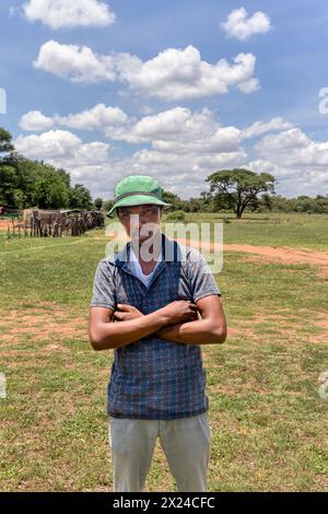 village jeune homme africain avec un sourire et les bras croisés dans le champ dans une journée d'été Banque D'Images