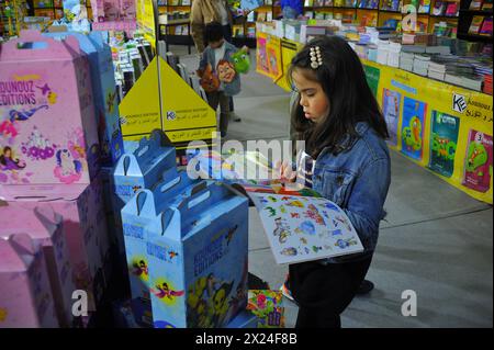 Tunis, Tunisie. 19 avril 2024. Une fille lit un livre à la Foire internationale du livre de Tunis, Tunisie, le 19 avril 2024. La 38ème édition de la Foire internationale du livre de Tunis a débuté vendredi au Parc des expositions du Kram à Tunis. Crédit : Adel Ezzine/Xinhua/Alamy Live News Banque D'Images