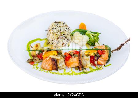 Brochettes grillées de singes et de saumon avec légumes assaisonnés et sauce picante. Banque D'Images