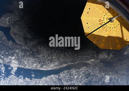 Atmosphère terrestre. 8 avril 2024. Une éclipse solaire totale est passée au-dessus de certaines parties du Mexique, des États-Unis et du Canada le 8 avril 2024. Des millions de personnes ont vu le ciel s'assombrir alors que la Lune passait entre la Terre et le Soleil, obscurcissant sa lumière brillante. Les astronautes à bord de la Station spatiale internationale ont eu une vue de haut en bas de l'ombre de la Lune alors qu'elle traversait l'Amérique du Nord. L'image ci-dessus, prise alors que la station spatiale orbite au-dessus de l'Atlantique Nord, montre l'ombre sombre de l'éclipse ainsi que l'horizon lumineux de la Terre, ou membre, à la limite entre l'atmosphère et l'espace. Un navire d'équipage accosté à th Banque D'Images