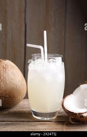 Verre d'eau de coco, glaçons et noix sur la table en bois Banque D'Images