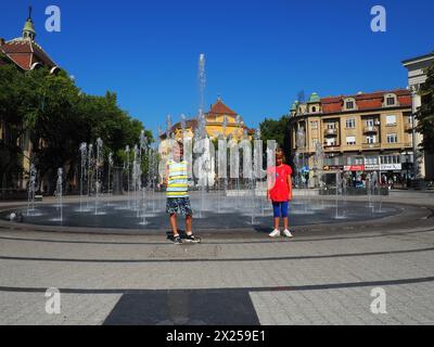 Subotica, Serbie, 12 septembre 2021. Fontaine sur la place de Subotica près de l'Hôtel de ville. Écoliers, garçon et fille, frère et soeur sont stan Banque D'Images