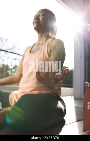 Une femme afro-américaine âgée aux cheveux gris courts médite à la maison Banque D'Images