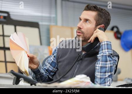 concepteur tenant des échantillons de couleur et parlant au téléphone Banque D'Images