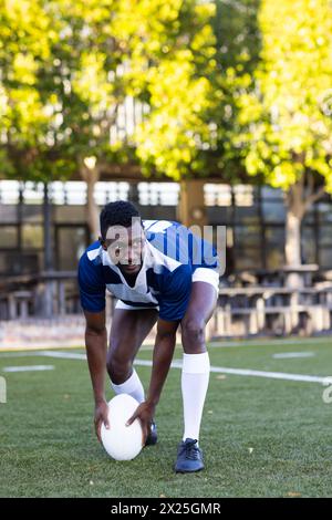 Jeune athlète afro-américain portant des vêtements de sport, s'étirant sur le terrain Banque D'Images