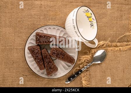 Quatre morceaux de gâteau gaufre au chocolat avec plaque en céramique et tasse sur toile de jute, vue de dessus Banque D'Images