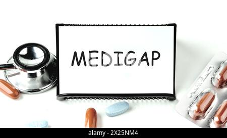 Concept médical. MEDIGAP sur une carte de visite sur un stand sur un fond blanc à côté de pilules, médicaments Banque D'Images