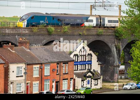 Un train inclinable Avanti Pendolino vu passer au-dessus du viaduc à la gare Runcorn avec des maisons blotties sous le pont. Banque D'Images