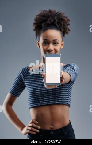 Une jeune femme excitée montre un smartphone, son expression reflétant la promesse de la communication moderne Banque D'Images