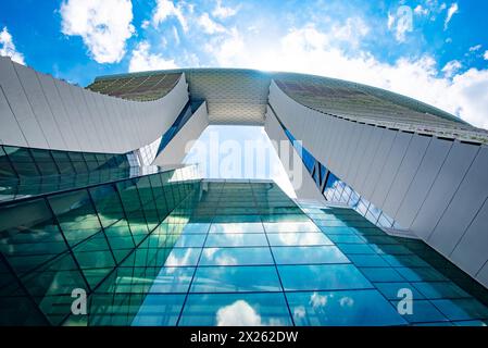 Les nuages se reflètent dans l'immense mur rideau de verre de l'hôtel Marina Bay Sands à Singapour. En regardant d'en bas. Banque D'Images