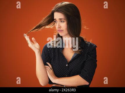 Studio, malheureux et femme avec les cheveux, les dommages et la perte de cheveux avec pointes fourchues, sec et traitement pour les soins capillaires. Fond rouge, maquette et fille avec texture Banque D'Images