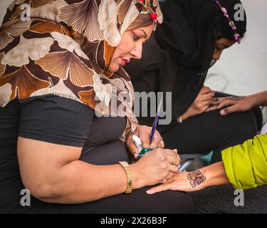 Londres, Royaume-Uni. 20 avril 2024. Les femmes pratiquant l'art de l'art corporel au henné décorent les mains avec un motif mehndi. Le festival annuel gratuit du maire de Londres revient à Trafalgar Square pour la 19ème année pour célébrer la fin du Ramadan, le mois sacré du jeûne. Crédit : Imageplotter/Alamy Live News Banque D'Images