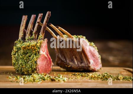 Carré cuit d'agneau avec croûte d'herbes de noisette sur planche de bois dans le restaurant Banque D'Images