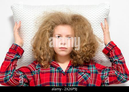 La fille se trouve rêvement sur un oreiller. La fille est allongée soigneusement sur l'oreiller. Il est temps de dormir. Banque D'Images