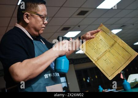 (240420) -- CHANGCHUN, 20 avril 2024 (Xinhua) -- Zhang Qi, restaurateur de livres anciens à la bibliothèque de l'Université de Jilin, pulvérise de l'eau sur les pages restaurées d'un livre ancien pour les aplatir à la bibliothèque de l'Université de Jilin à Changchun, dans la province de Jilin au nord-est de la Chine, 19 avril 2024. L'Université Jilin possède une collection de près de 400 000 livres anciens dans sa bibliothèque. Selon Zhang Qi, restaurateur de livres anciens à la bibliothèque de l'Université de Jilin, l'école effectue des travaux de restauration de livres anciens depuis les années 1950, qui n'ont jamais été interrompus depuis des décennies. G Banque D'Images