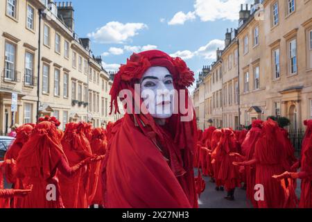 Bath, Royaume-Uni. 20 avril 2024. Vêtus de leurs tenues rebelles rouges distinctives, le plus grand rassemblement mondial de la Brigade rebelle rouge jamais vu (400 au total) sont photographiés alors qu'ils prennent part à une procession « funérailles pour la nature » dans les rues de Bath pour aider à sensibiliser aux dommages que l'humanité fait à la planète. L’événement était prévu pour coïncider avec le jour de la Terre et la procession de Bath sera rejointe par le militant de la nature Chris Packham qui livrera un «éloge» à la foule lors de la finale de l’événement lorsqu’il arrivera devant l’abbaye de Bath. Crédit : Lynchpics/Alamy Live News Banque D'Images