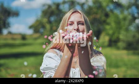 Une fille souffle des confettis en papier multicolores de ses mains. Banque D'Images