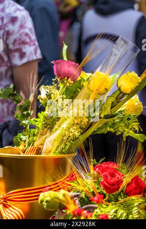 Roses jaunes et rouges dans un pot d'or avec un arc du drapeau de la Catalogne à un stand de fleurs de la fête traditionnelle de Catalogne avec beaucoup de gens w Banque D'Images