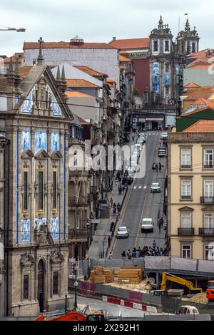 Rue touristique escarpée avec les rails de tramway à Porto à l'aube, avec le ciel nuageux et les églises typiques ornées de carreaux bleus et blancs. Portugal. Banque D'Images