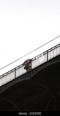 Femme d'âge moyen portant un parapluie le long de la plate-forme supérieure du pont en acier Don Luis I à Porto avec des détails de sa structure métallique et de l'AC Banque D'Images