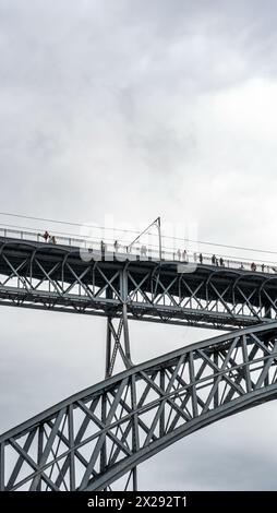 Touristes marchant, prenant des photos et une femme posant depuis la plate-forme supérieure du pont en acier Don Luis I où le métro de Porto passe avec le nuage de pluie Banque D'Images