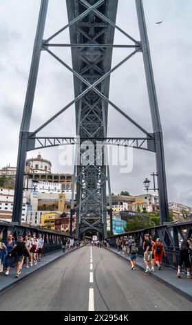 Touristes marchant le long de la plate-forme inférieure avec une vue sur la structure métallique du pont en acier Don Luis I à Porto avec des nuages de pluie dans le backgroun Banque D'Images
