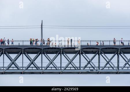 Touristes marchant, prenant des photos et se penchant sur la balustrade du pont en acier Don Luis I à Porto avec des nuages de pluie en arrière-plan pour voir le Dou Banque D'Images